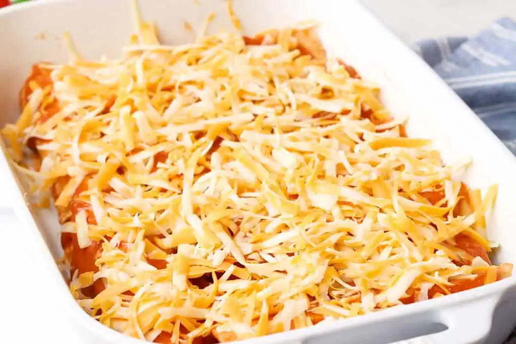 cheese over unbaked enchiladas in a casserole dish