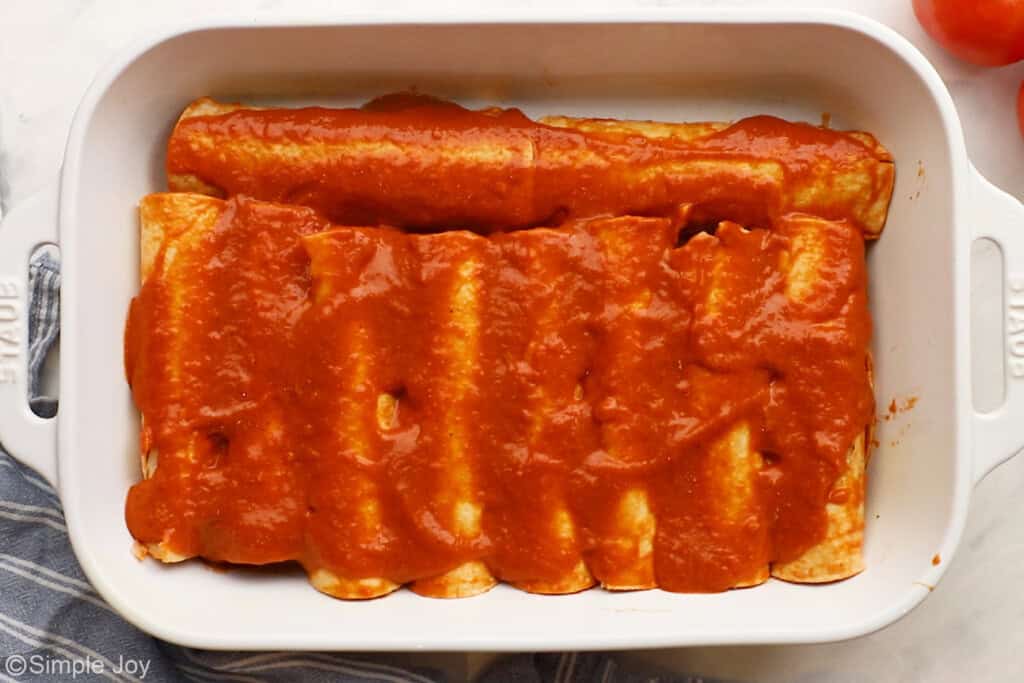 enchilada sauce over unbaked enchiladas in a casserole dish