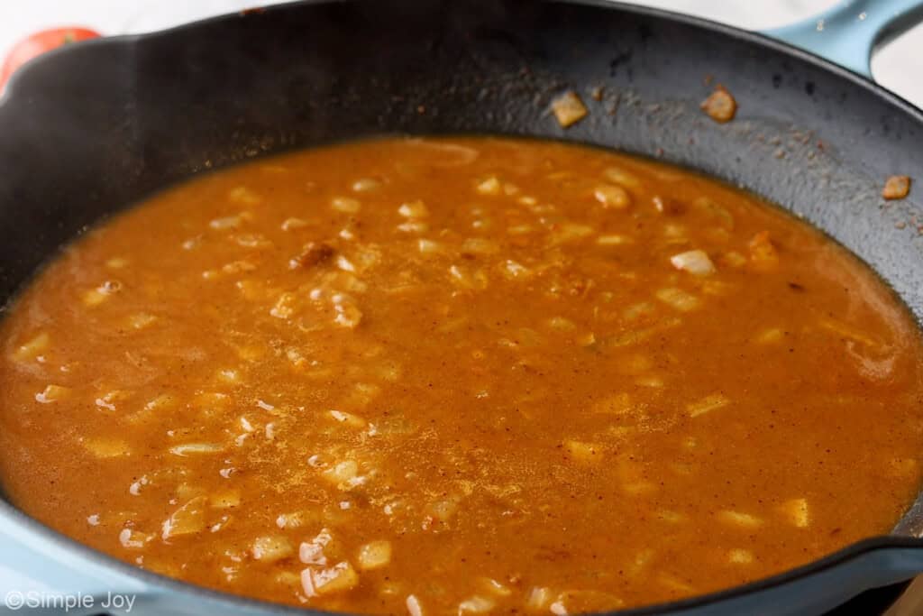 chicken stock added to a skillet to make enchilada sauce