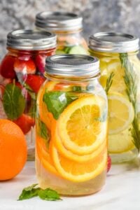 four mason jars filled with water and fruit to make infused water recipes