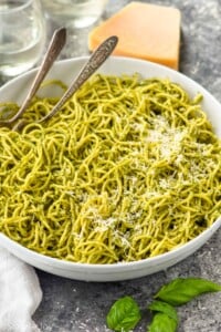 bowl of pesto pasta topped with parmesan cheese