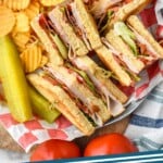 Pinterest graphic for Club Sandwich. Image shows overhead of club sandwich with chips and pickle spears in a basket. Text says "club sandwich simplejoy.com"