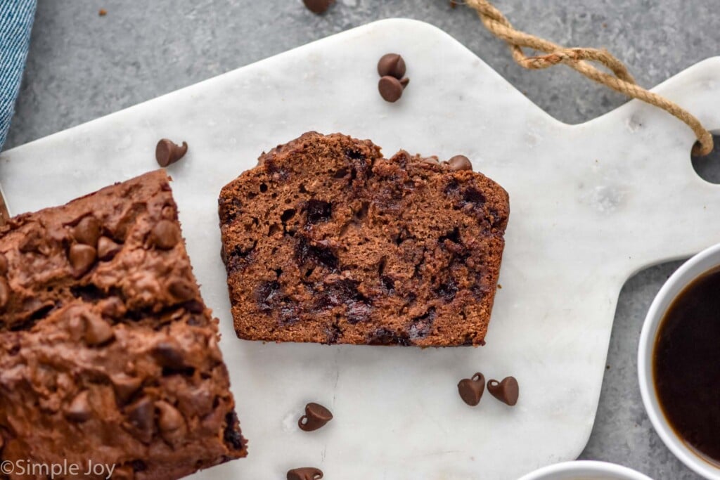 Overhead view of a loaf and slice of Chocolate Banana Bread on serving board.