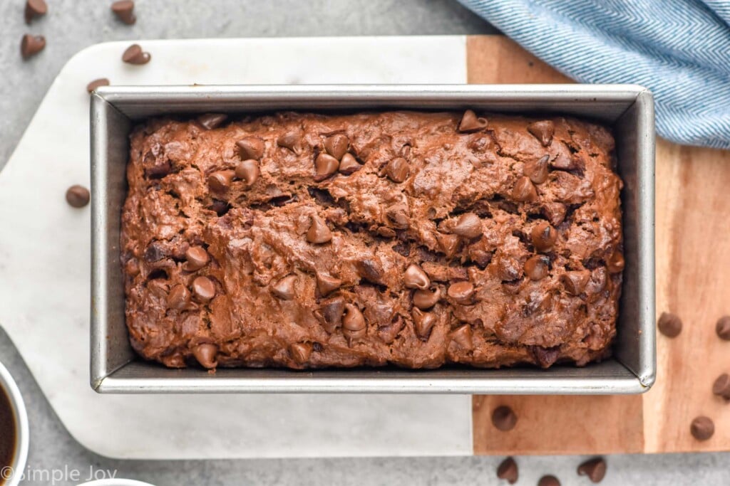 overhead of a loaf of Chocolate Banana Bread in a bread pan on a serving board