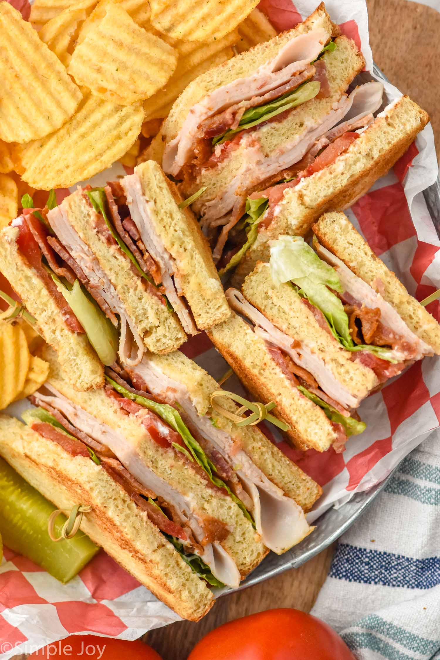 overhead view of club sandwich with chips and a pickle spear