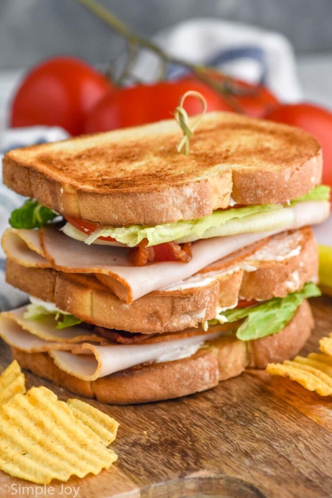 club sandwich with chips and tomatoes in the background