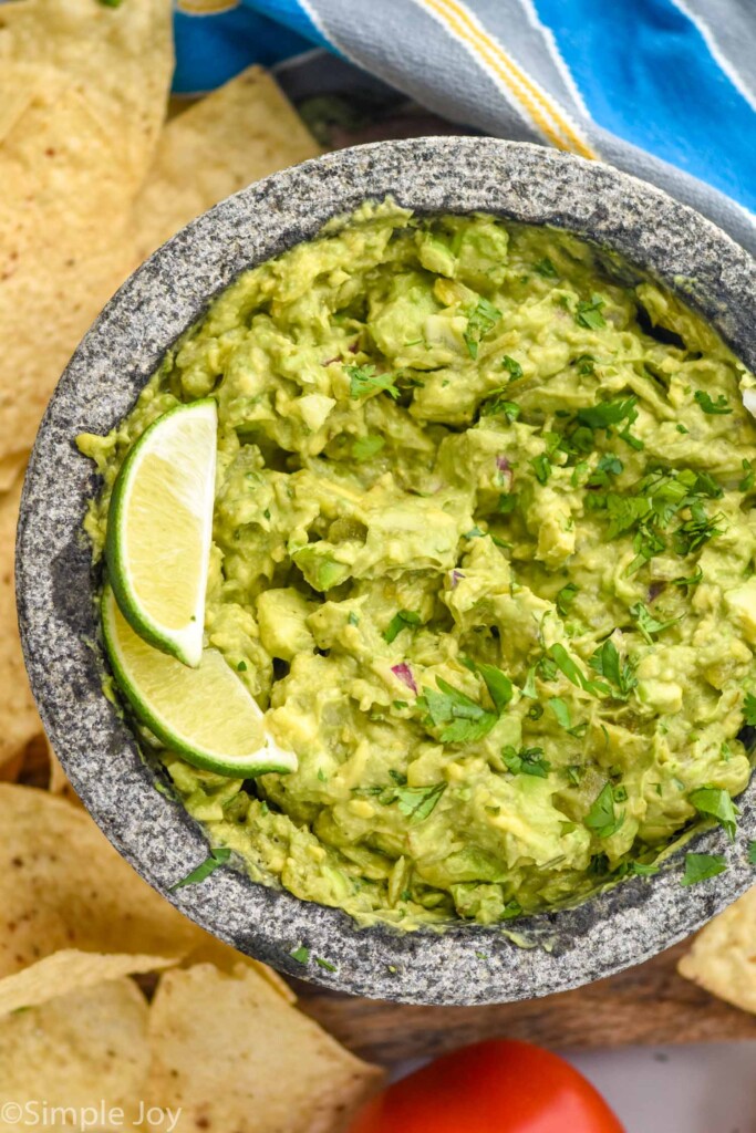 Overhead photo of Easy Guacamole Recipe garnished with lime wedges and chips.