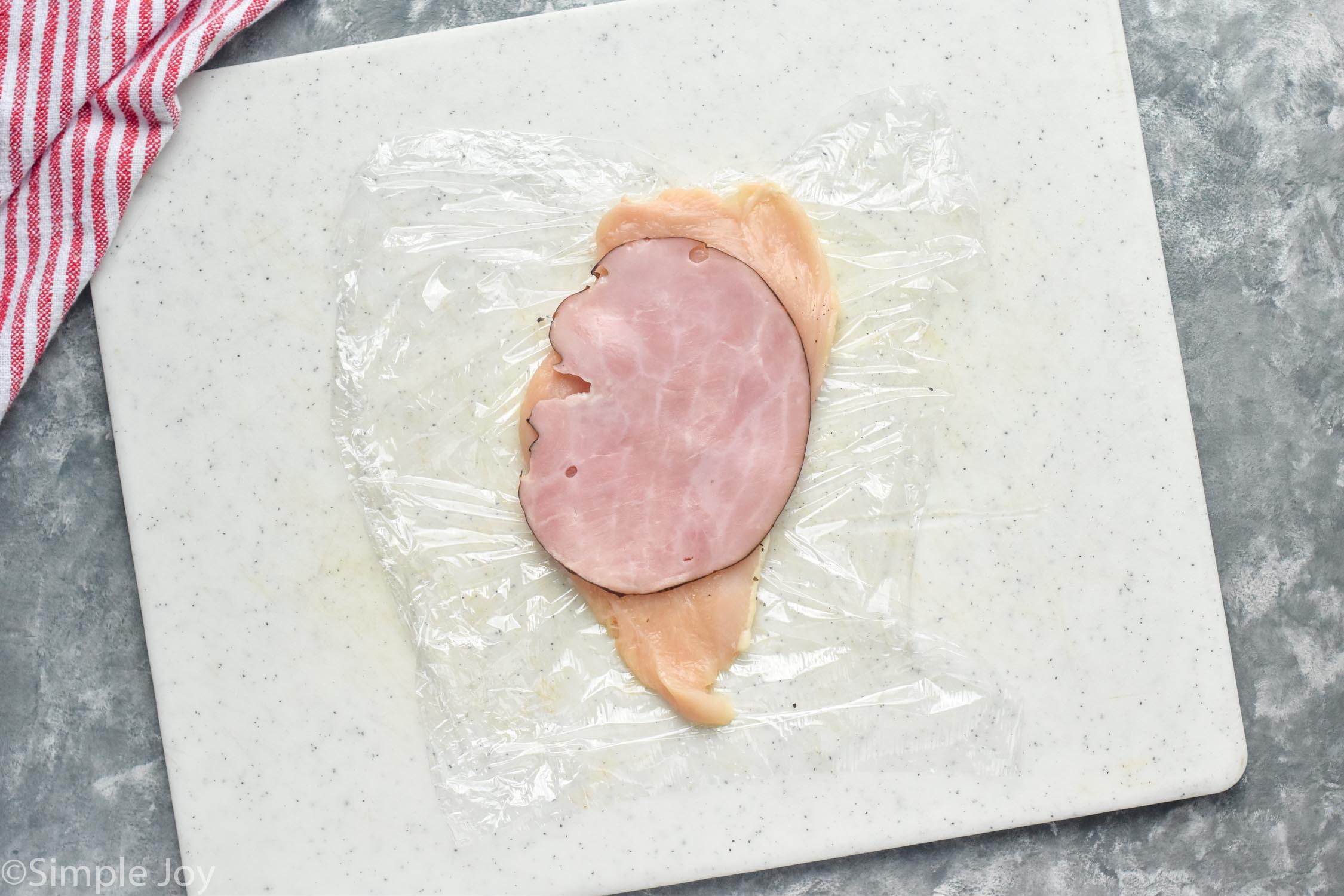 overhead view of chicken cutlet with slice of ham on it to make Chicken Cordon Bleu