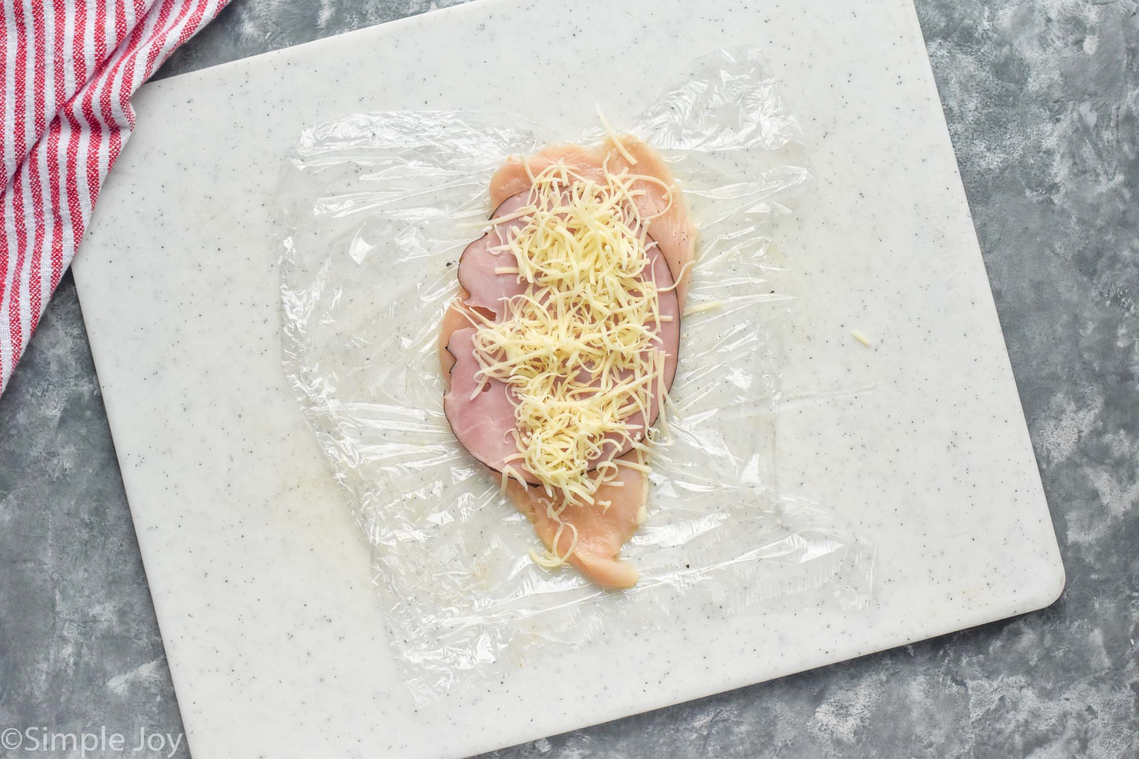 overhead view of chicken cutlet topped with Chicken Cordon Bleu ingredients to make Chicken Cordon Bleu