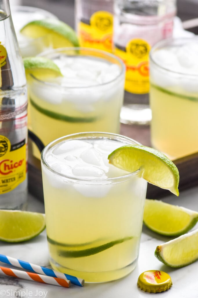 Glass of Ranch Water drink with ice and lime wedge. Ranch Water ingredients sitting in background