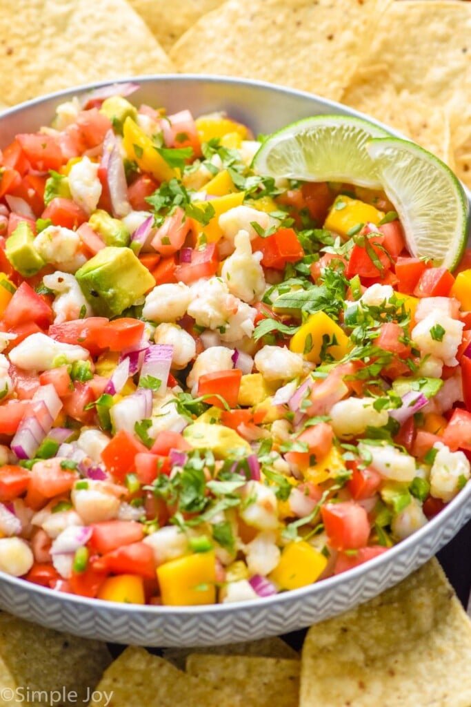 Bowl of Shrimp Ceviche garnished with two lime wedges, surrounded by tortilla chips