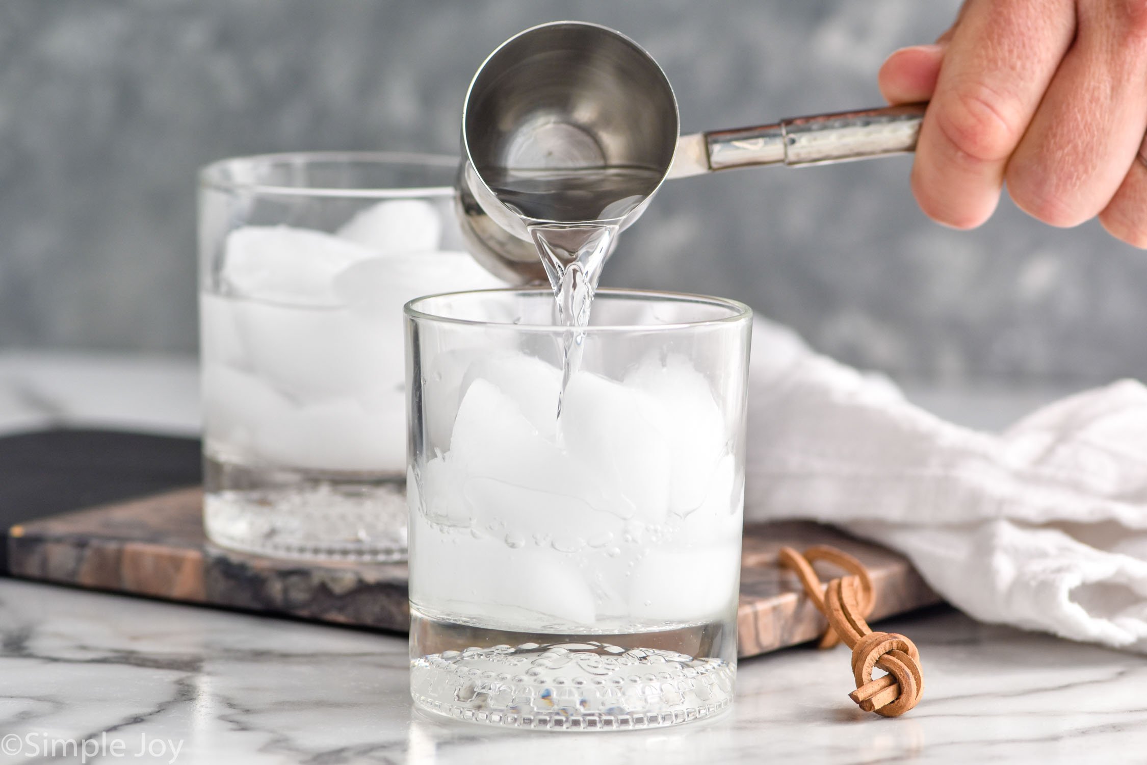 Man's hand pouring vodka into a glass of ice to make a white russian