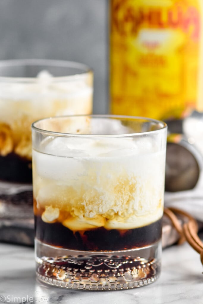 two glasses of White Russian cocktail with bottle of Kahlua