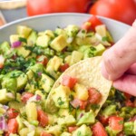 Pinterest graphic for Avocado Salsa recipe. Text says, "the best Avocado Salsa simplejoy.com." Image shows person's hand scooping Avocado Salsa with a tortilla chip from a bowl of Avocado Salsa.