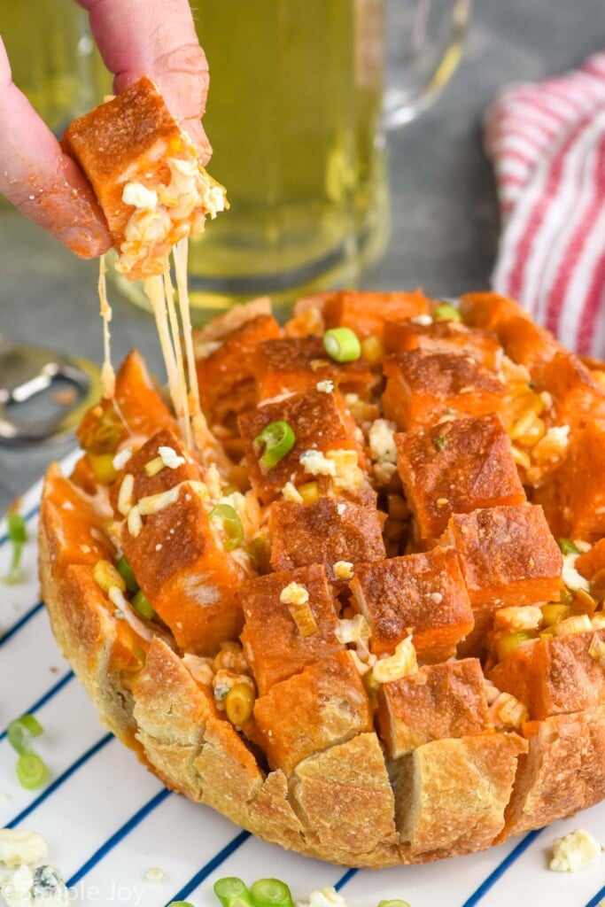 man's hand pulling piece of Buffalo Pull Apart Bread from loaf