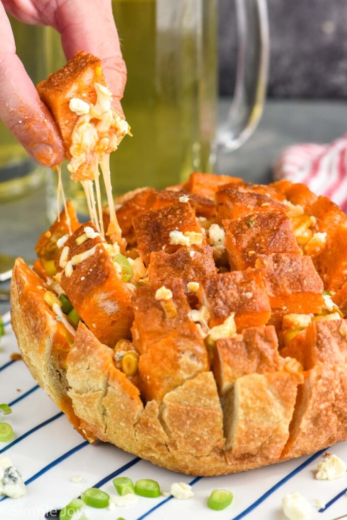 man's hand pulling piece of Buffalo Pull Apart Bread from loaf