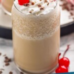 Pinterest graphic for Bushwacker recipe. Image is photo of Bushwacker garnished with a cherry and straws. Text says, "Bushwacker cocktail simplejoy.com"