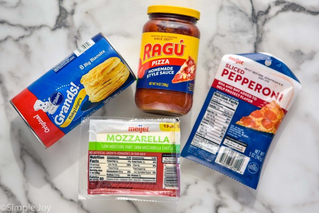 Overhead photo of ingredients for Mini Calzones on the counter: biscuits, mozzarella cheese, pizza sauce, and pepperoni.