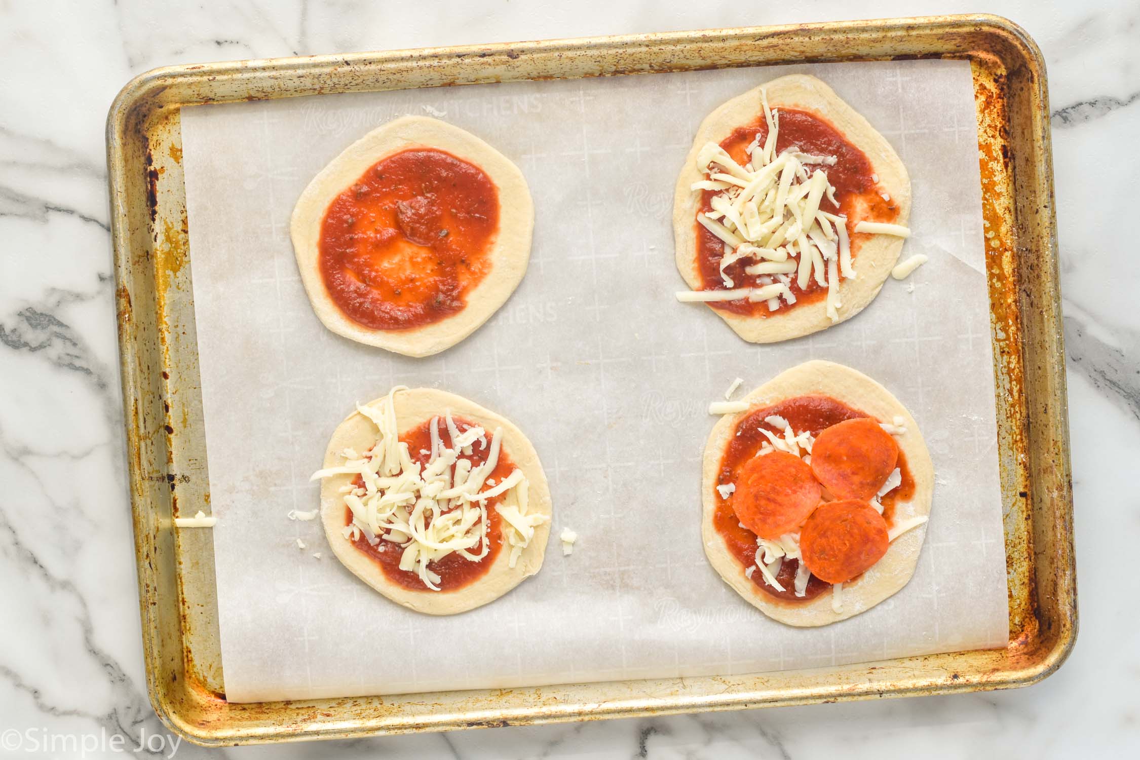 Overhead photo of a baking sheet with ingredients for Mini Calzones recipe.