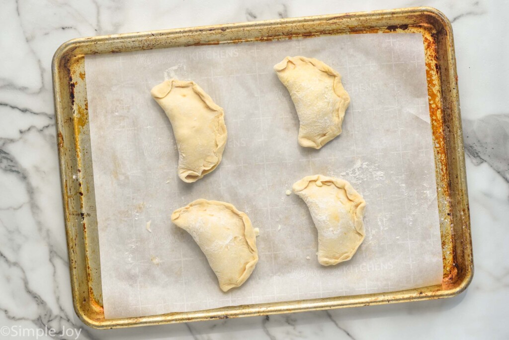 Overhead photo of a baking sheet with Mini Calzones recipe before baking.