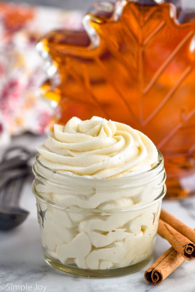 jar of maple frosting. Cinnamon sticks sitting beside