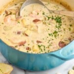 Pinterest graphic for Seafood Chowder Recipe. Image shows a pot of Seafood Chowder with a ladle. Salad, bread, and oyster crackers beside pot. Text says, "the best Seafood Chowder simplejoy.com"