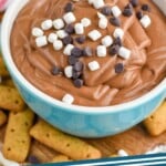 Pinterest graphic for S'mores Dip recipe. Image is photo of a bowl of S'mores Dip garnished with mini marshmallows and chocolate chips with graham crackers beside bowl for dipping. Text says, "S'mores Dip simplejoy.com"
