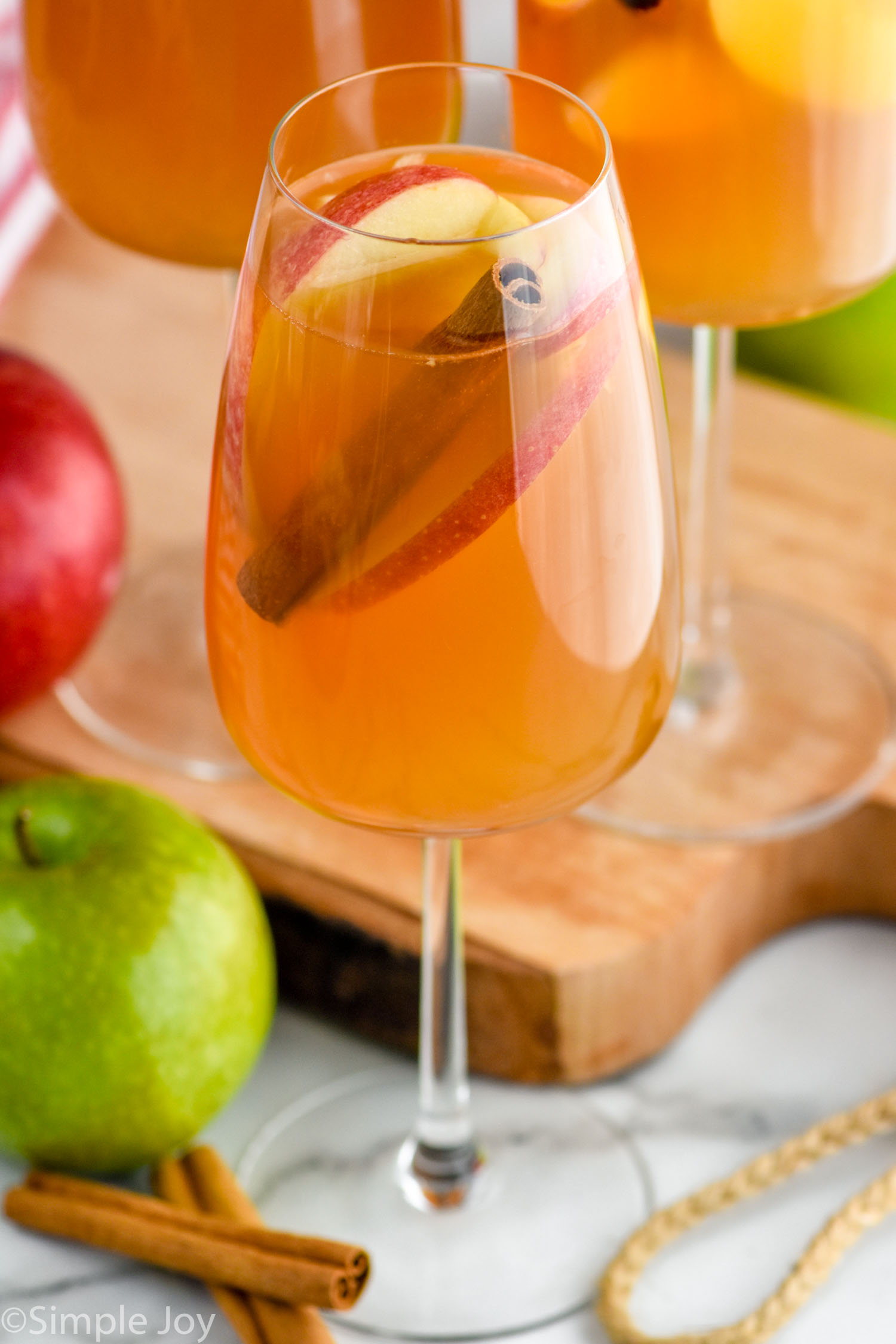 Photo of a glass of Apple Cider Sangria garnished with apples slices and cinnamon sticks.