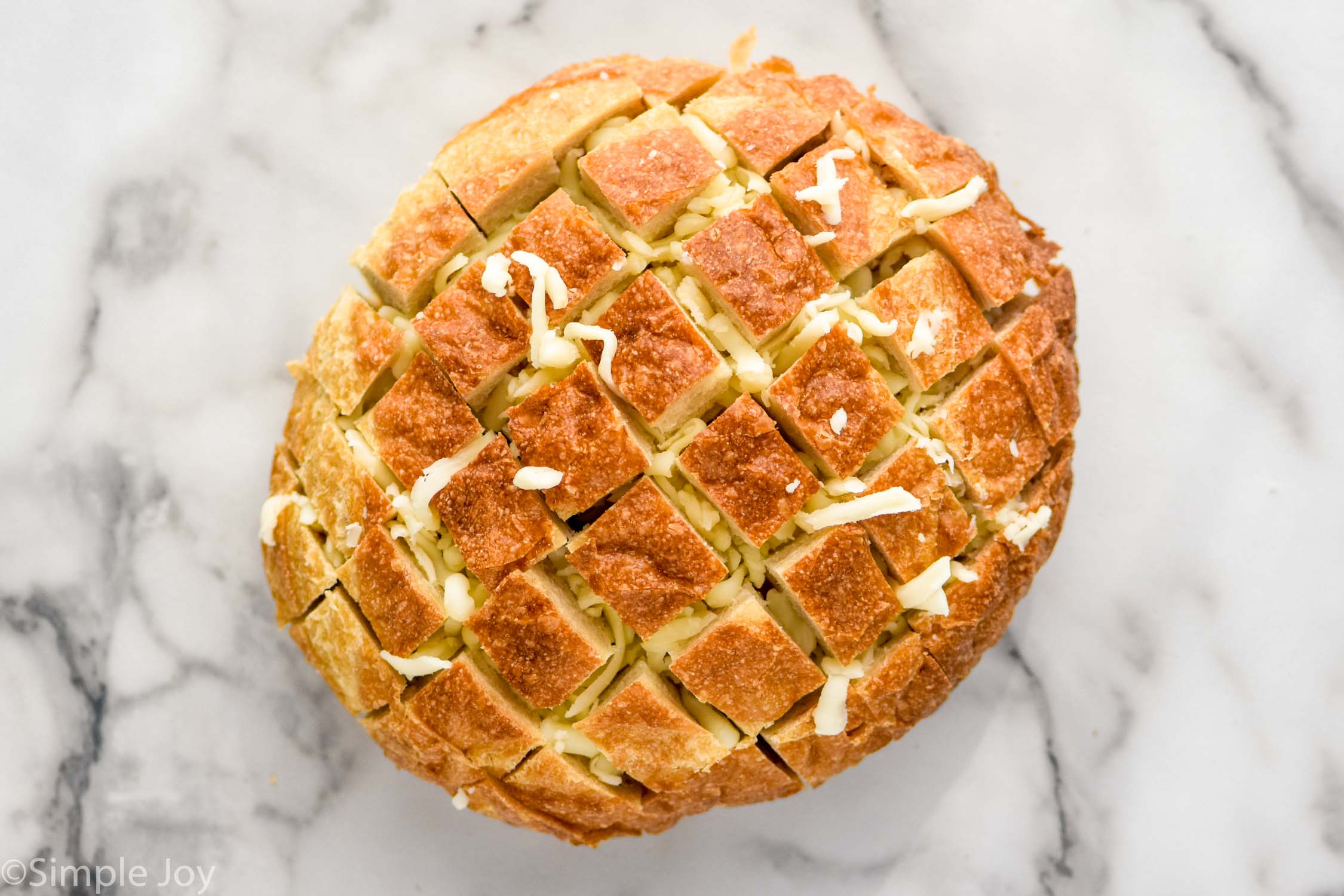 overhead of loaf of artisan bread with cheese to make Buffalo Pull Apart Bread