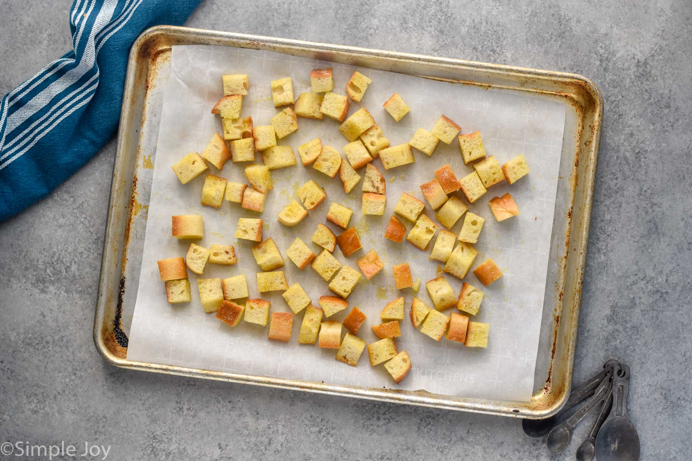 Overhead photo of a baking sheet of bread cubes for Croutons recipe.