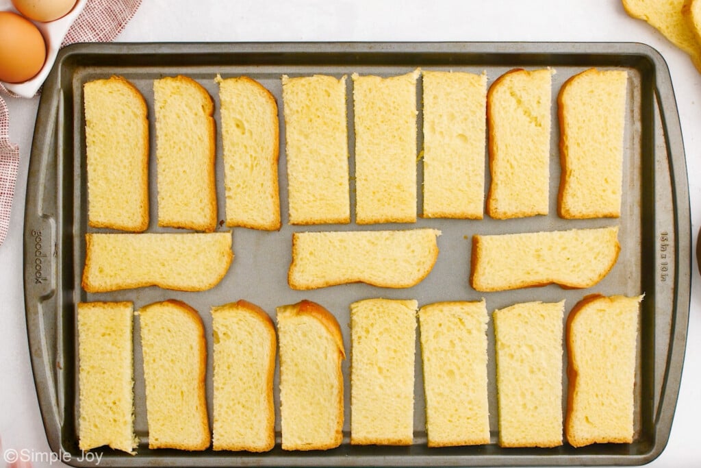 overhead of rimmed baking sheet of bread drying to make french toast sticks - 6