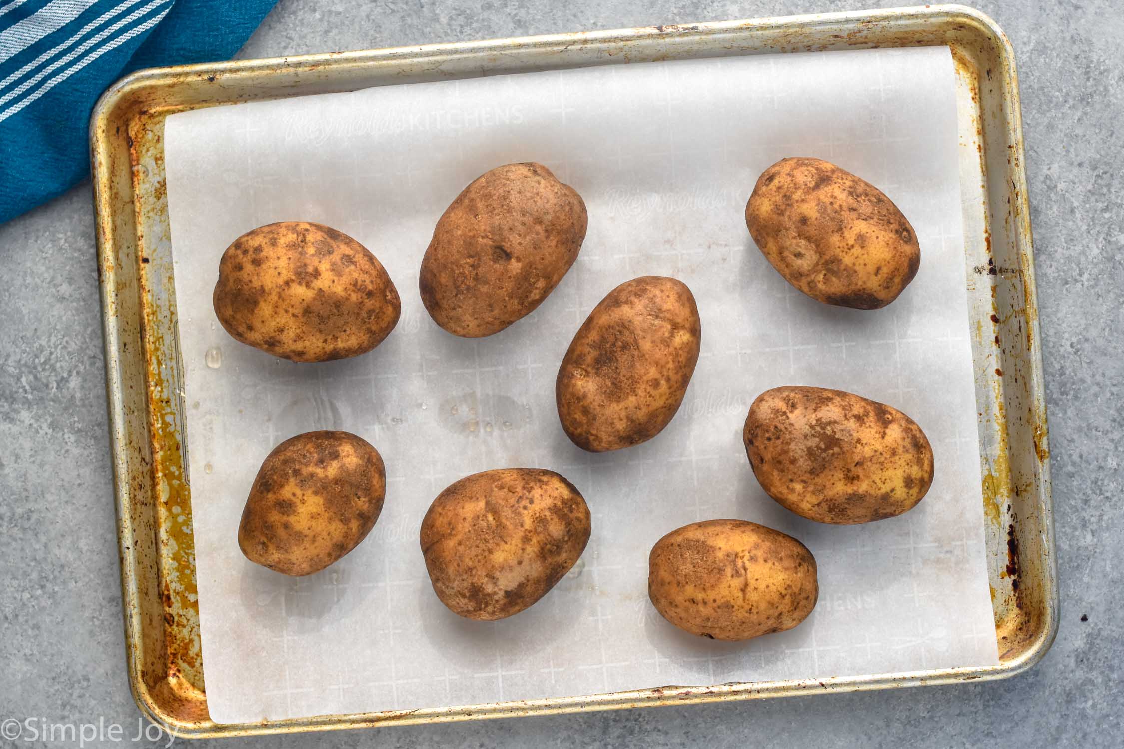 Overhead photo of a baking sheet of potatoes for Potato Skins recipe.
