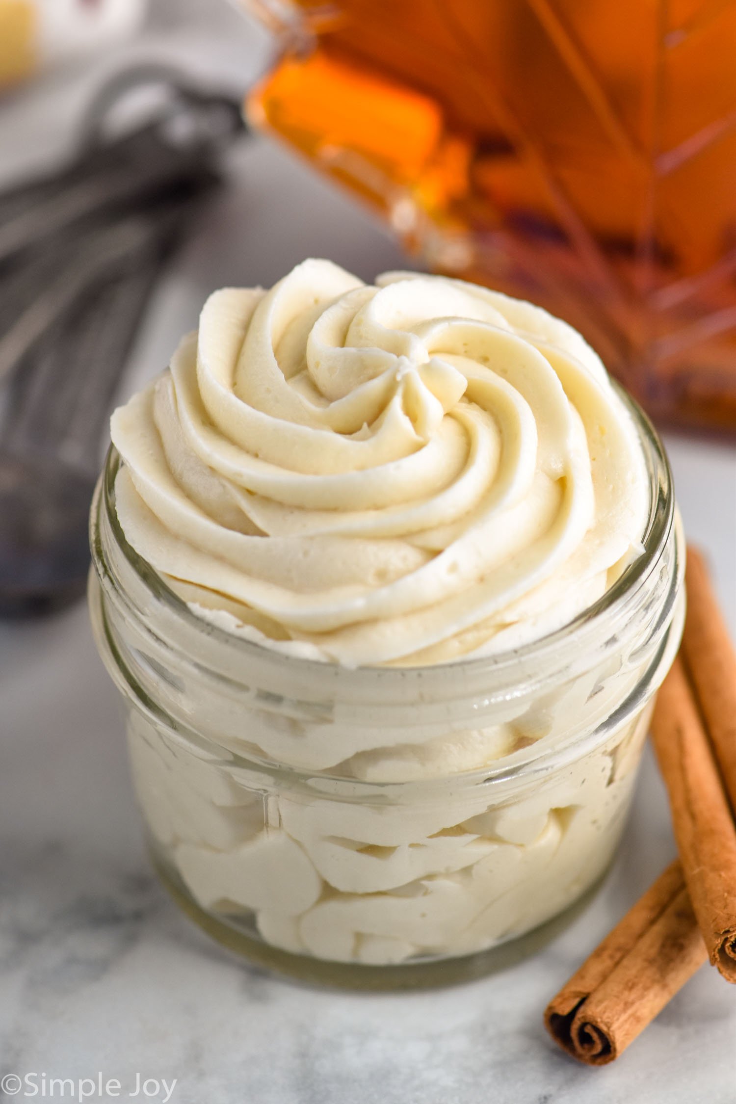 jar of maple frosting. Cinnamon sticks sitting beside