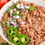 bowl of instant pot pinto beans topped with cilantro, red onion, and cilantro - 14