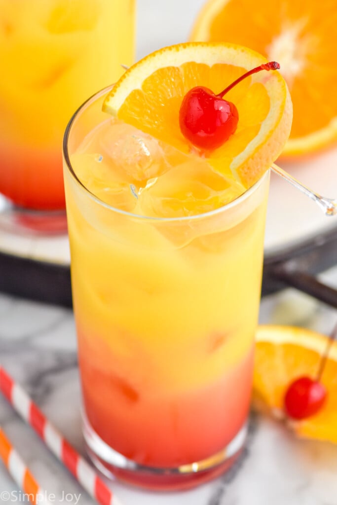 Photo of Tequila Sunrise garnished with orange slice and cherry.