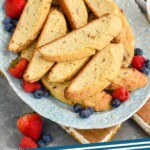 Pinterest graphic for Biscotti recipe. Image shows platter of Biscotti with fruit. Cup of coffee and bowl of fruit beside. Text says, "the best Biscotti simplejoy.com"