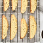 Pinterest graphic for Biscotti recipe. Image is overhead photo of Biscotti on a cooling rack with cups of coffee beside. Text says, "super easy Biscotti recipe simplejoy.com"