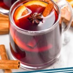 Pinterest graphic for Slow Cooker Mulled Wine recipe. Image shows a mug of Slow Cooker Mulled Wine with cinnamon sticks and orange slices beside. Text says, "Mulled Wine simplejoy.com"