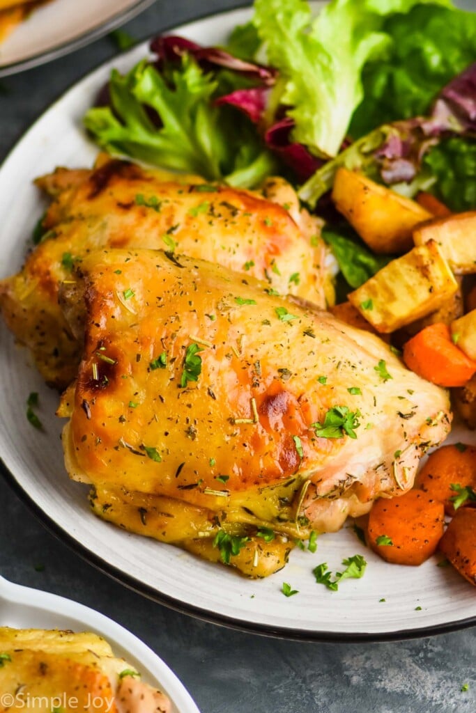 Photo of Baked Chicken Thighs served on a plate with veggies and side salad