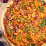 overhead of BBQ Chicken Pizza with bottle opener and bottle of beer sitting beside