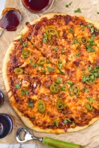 overhead of BBQ Chicken Pizza with bottle opener and bottle of beer sitting beside