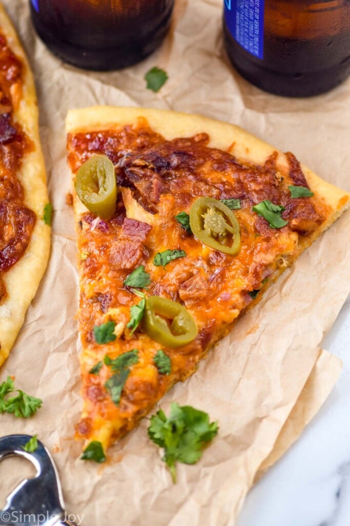 slice of BBQ Chicken Pizza with bottle opener and bottle of beer sitting beside