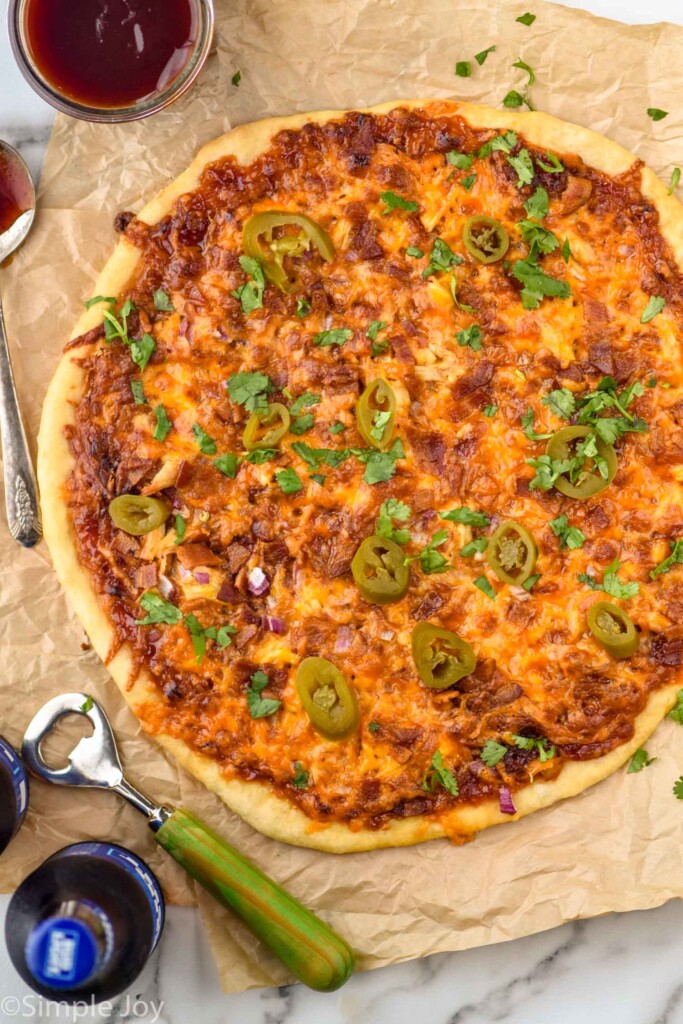 overhead of BBQ Chicken Pizza with bottle opener and bottle of beer sitting beside