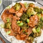 Plate of Chicken and Broccoli Recipe served on rice. Drinks beside plate.