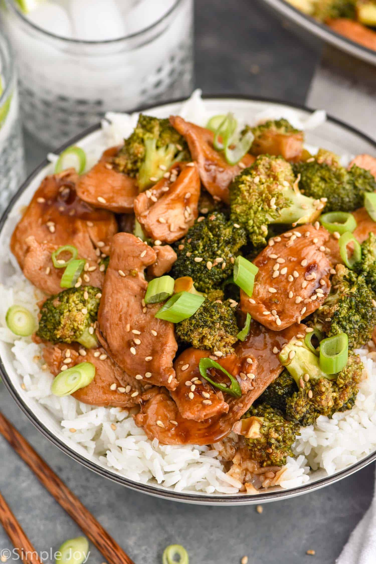 Plate of Chicken and Broccoli Recipe served on rice. Drinks beside plate.