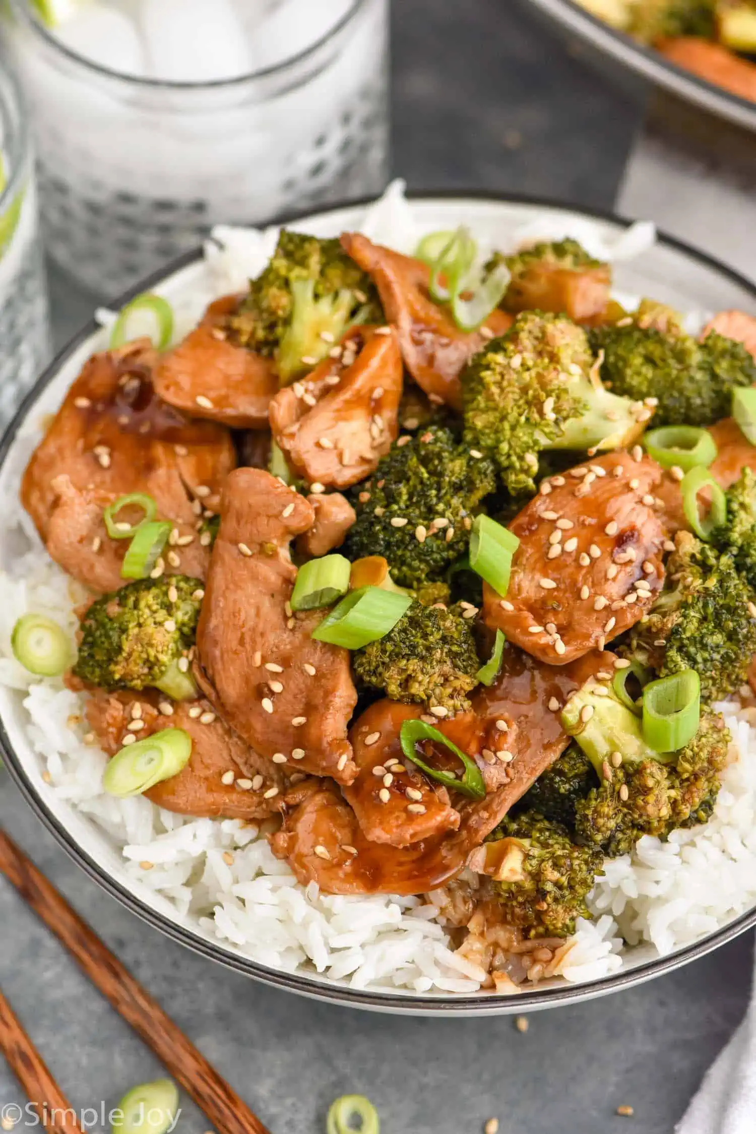 Plate of Chicken and Broccoli Recipe served on rice. Drinks beside plate.