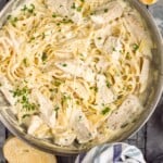 Overhead photo of a skillet of Chicken Alfredo with bread beside - 10