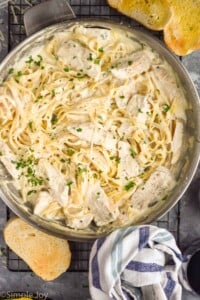 Overhead photo of a skillet of Chicken Alfredo with bread beside