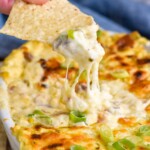 person's hand holding chip with corn dip out of a dish of hot corn dip - 21