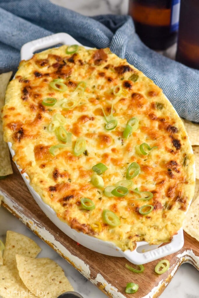 dish of hot corn dip with tortilla chips sitting beside